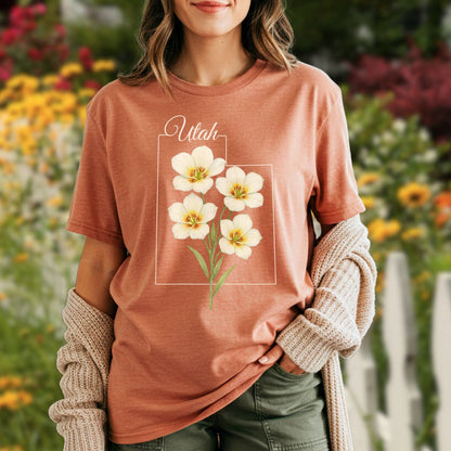 Garment-dyed rust t-shirt with watercolor Sego Lily flowers inside a Utah outline.
