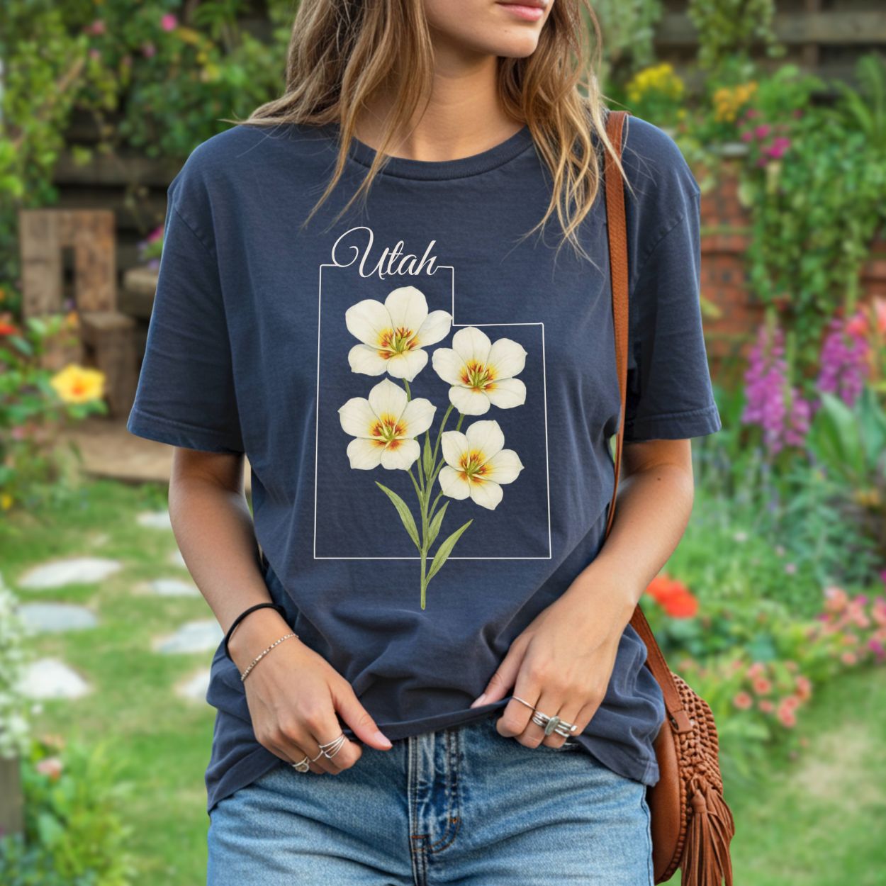 Navy blue relaxed-fit t-shirt with watercolor Sego Lily flowers and "Utah" text, worn by a woman.