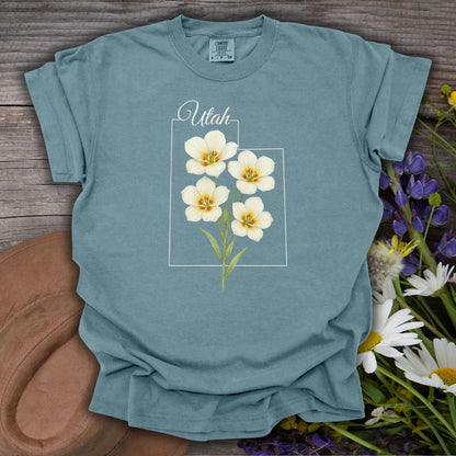 Ice Blue Sego Lily Utah t-shirt with watercolor flowers, on wood with a hat and wildflowers.