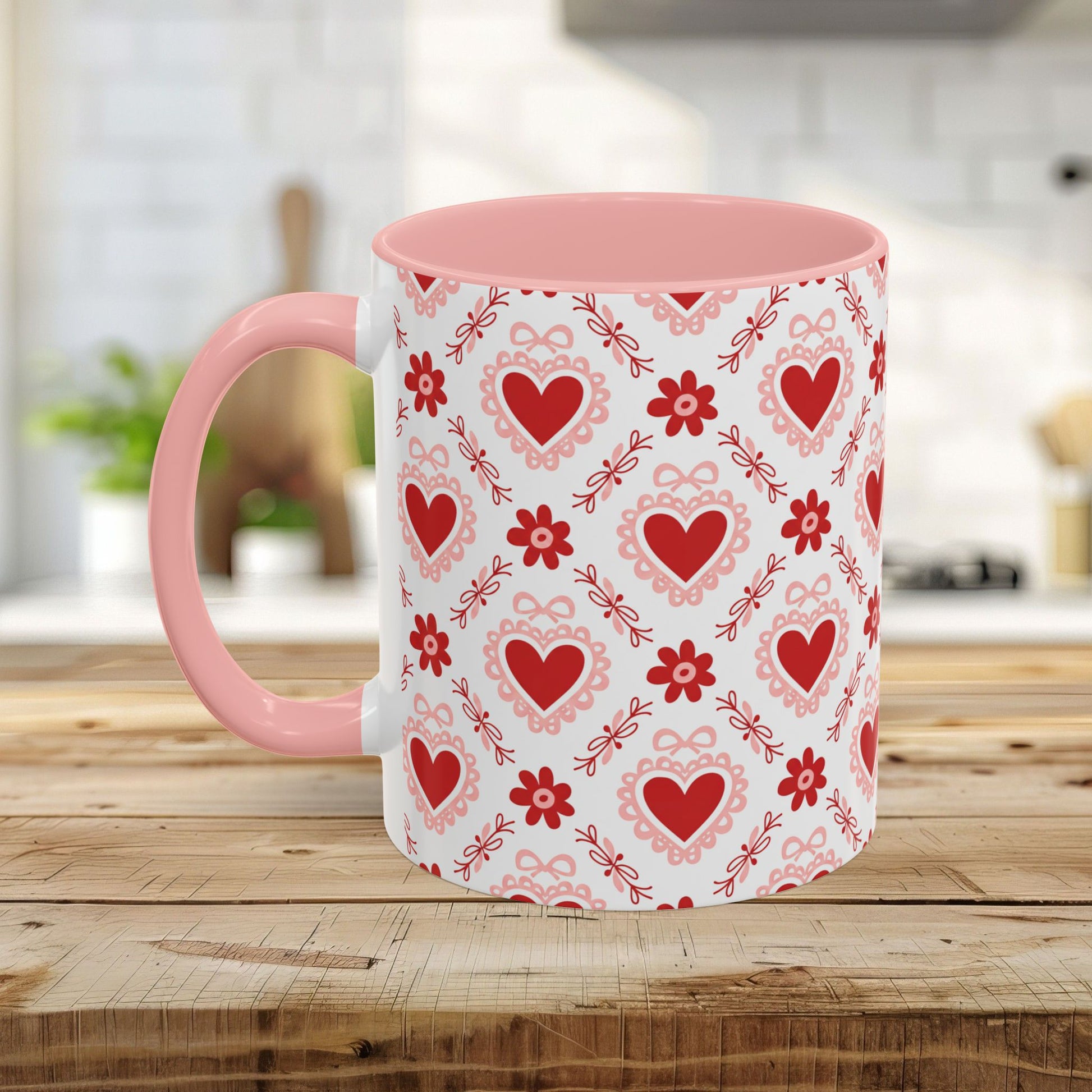 Ceramic mug with a pink handle and interior, featuring a repeating pattern of red hearts, floral motifs, and bows.