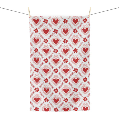 Microfiber tea towel with a repeating pattern of red hearts and small floral motifs, hanging on a clothesline.