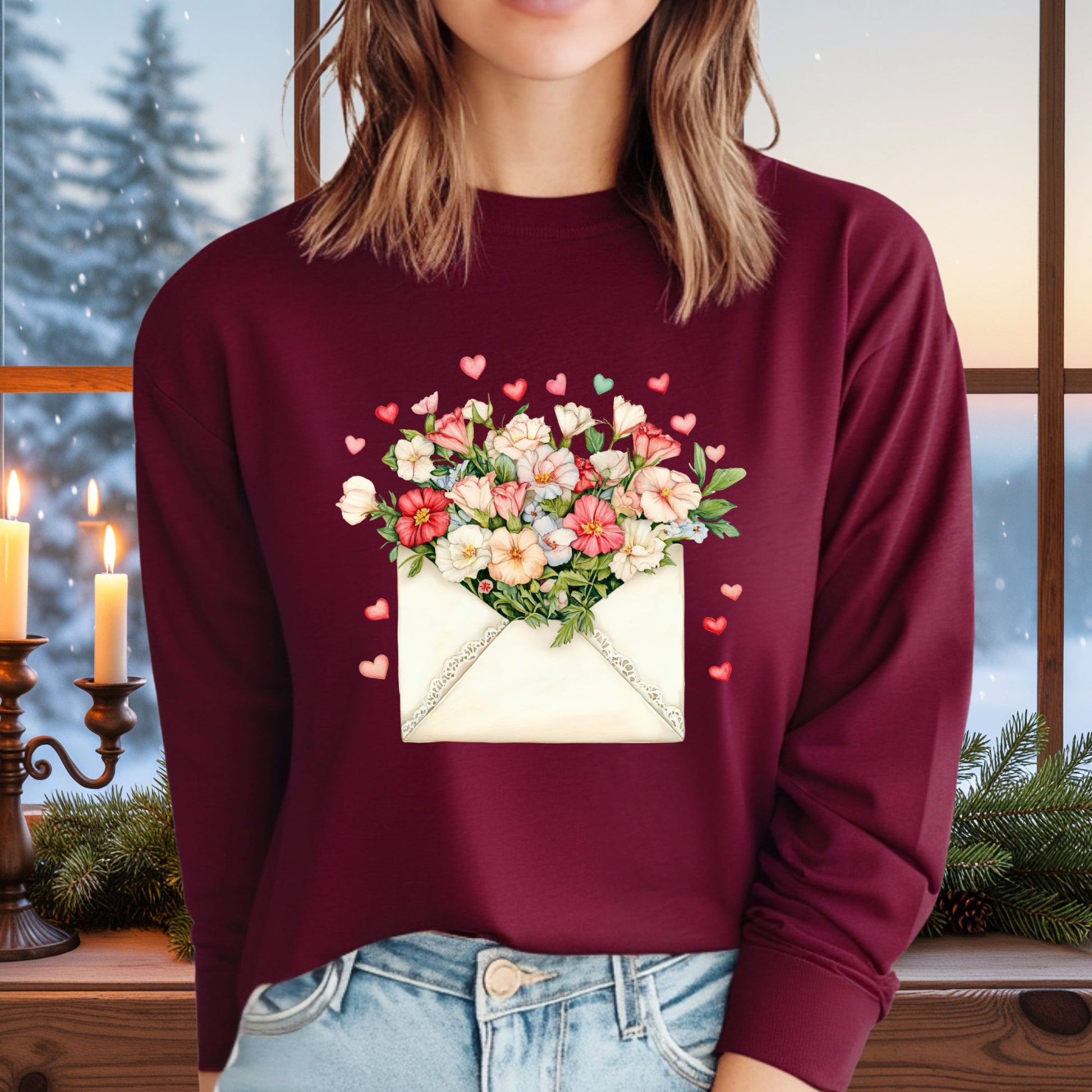 Maroon long-sleeve tee with a vintage envelope design spilling pink and cream flowers and hearts.