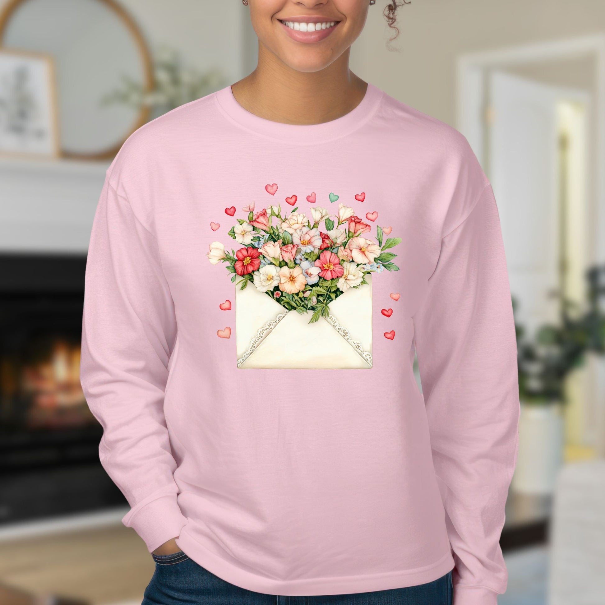 Pink long sleeve tee with a vintage envelope design spilling hand-drawn hearts and pink and cream blooms.