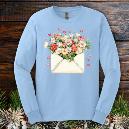 Light blue long sleeve tee with a vintage envelope spilling pink and cream flowers and hearts.