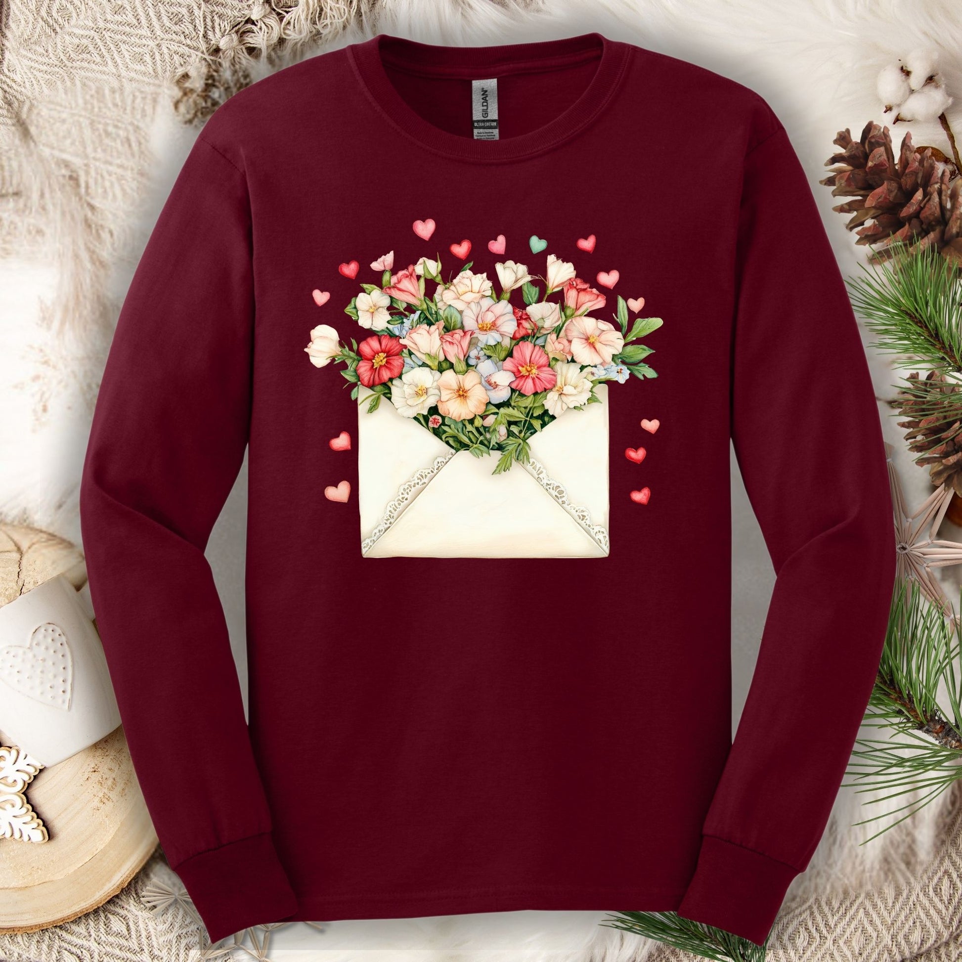 Maroon long-sleeve tee with a vintage envelope design spilling pink and cream flowers and hearts.