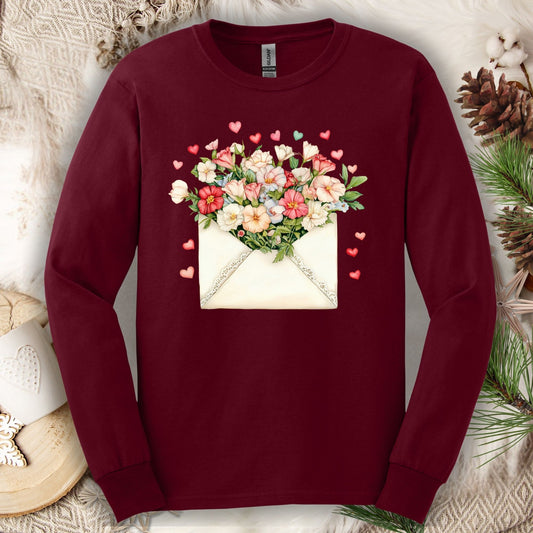 Maroon long-sleeve tee with a vintage envelope design spilling pink and cream flowers and hearts.