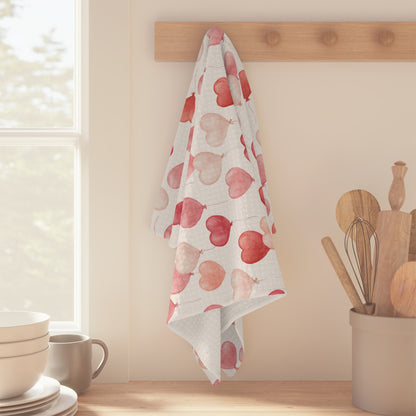 Microfiber tea towel with a watercolor pink and red heart balloon pattern, hanging on a wooden peg rail.