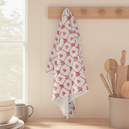 White microfiber tea towel with red geometric heart pattern hanging on a wooden peg rack.