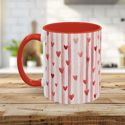 Glossy white ceramic mug with watercolor pink stripes and red hearts, red interior and C-shaped handle.