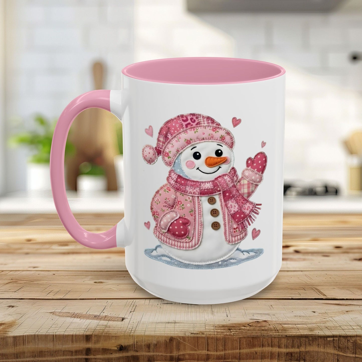 White ceramic mug with pink handle and interior, featuring a smiling patchwork snow lady in a pink hat and jacket.