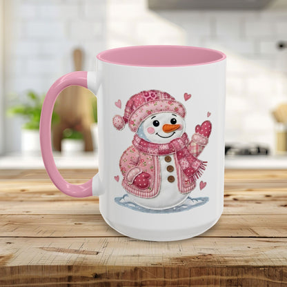White ceramic mug with pink handle and interior, featuring a smiling patchwork snow lady in a pink hat and jacket.