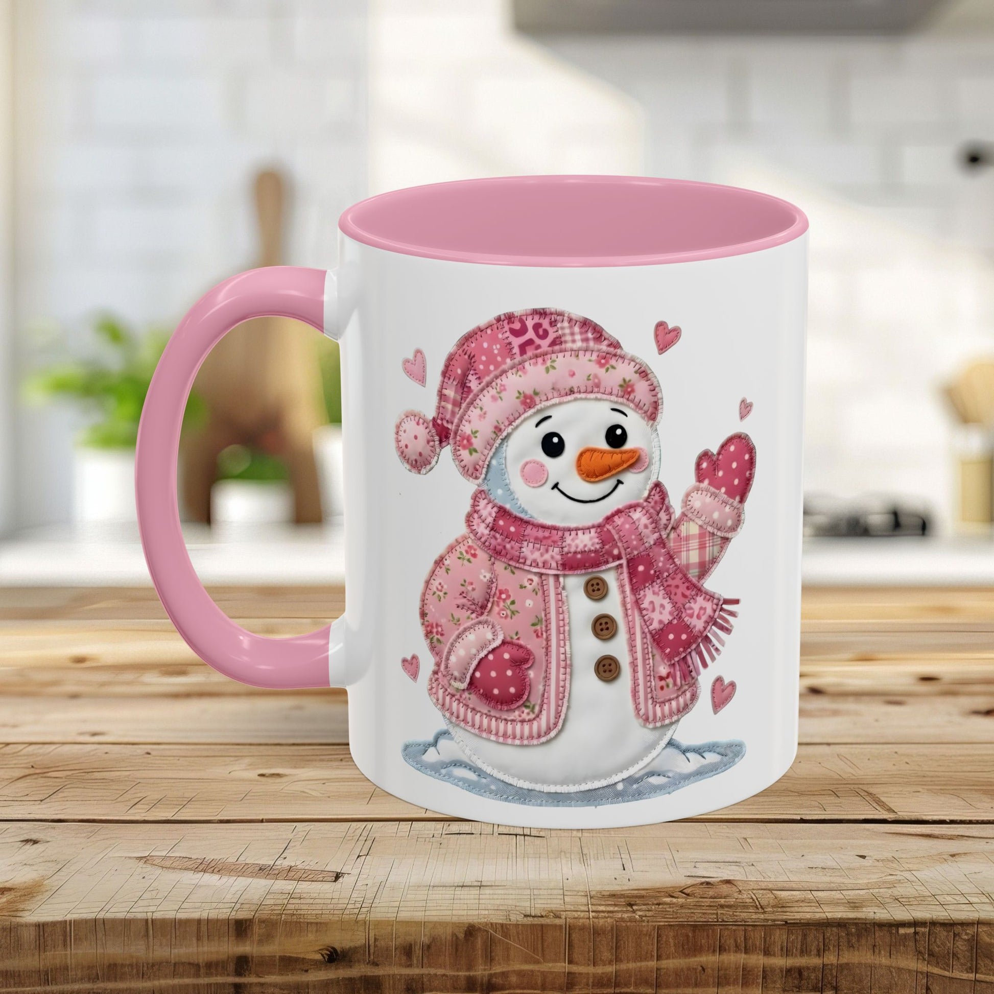 White ceramic mug with pink handle and interior, featuring a rosy patchwork snow lady design.