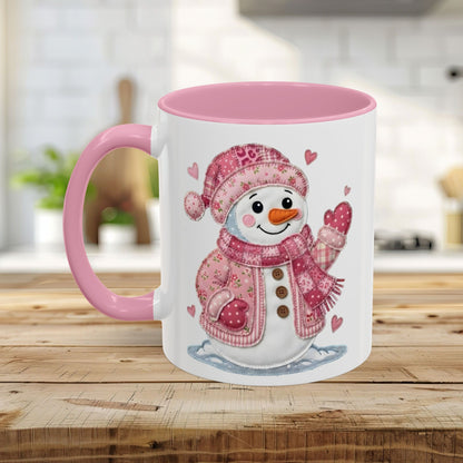 White ceramic mug with pink handle and interior, featuring a rosy patchwork snow lady design.