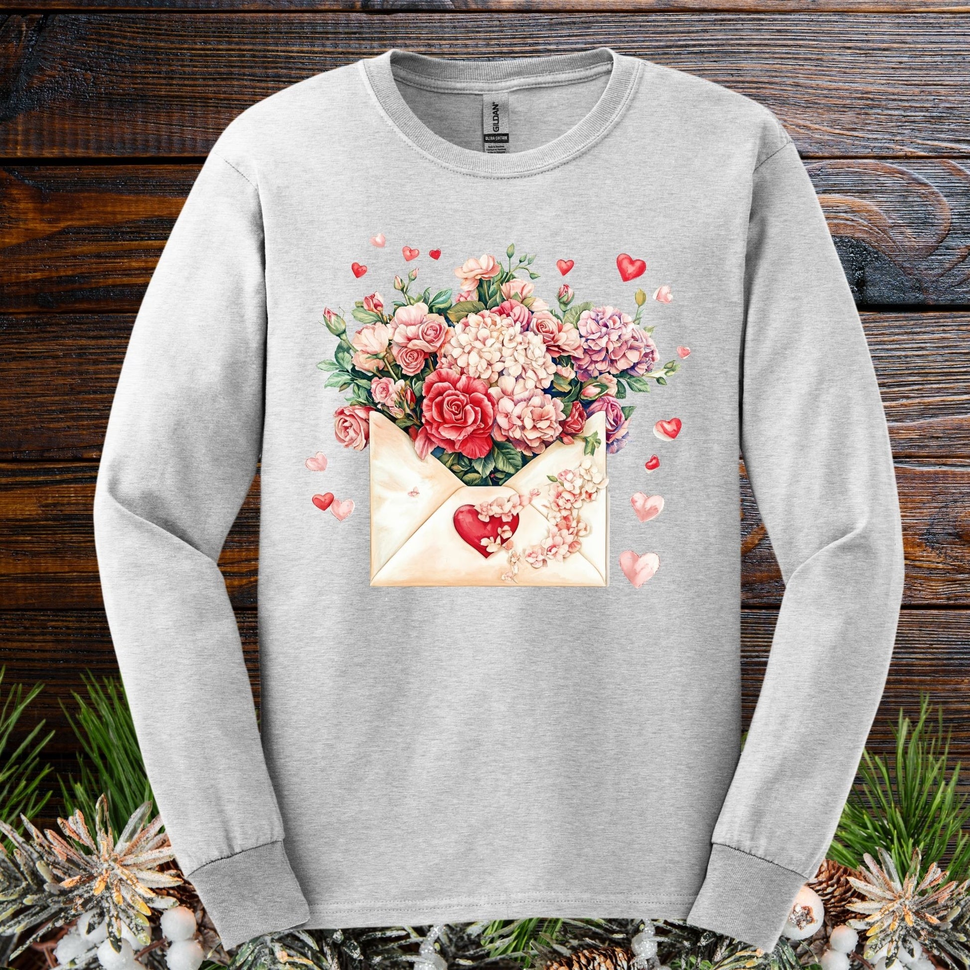 Ash long sleeve tee with a vintage heart envelope overflowing with red, ivory, and pink flowers.