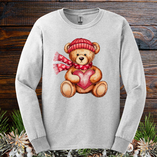 Ash long sleeve tee with watercolor teddy bear holding a red heart, wearing a red hat and scarf.