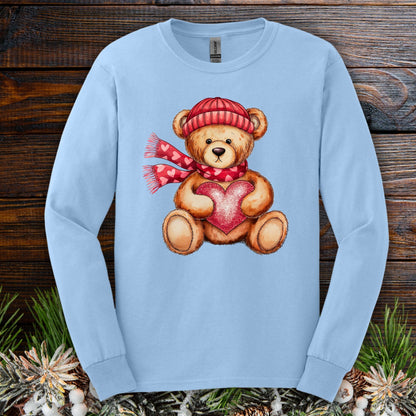 Light blue long sleeve tee with a watercolor teddy bear holding a red heart, wearing a red hat and scarf.