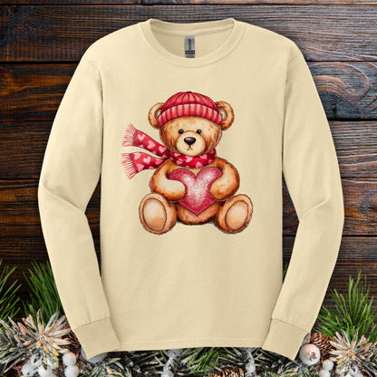 Sand long-sleeve tee with watercolor teddy bear holding a red heart, wearing a red hat and scarf.