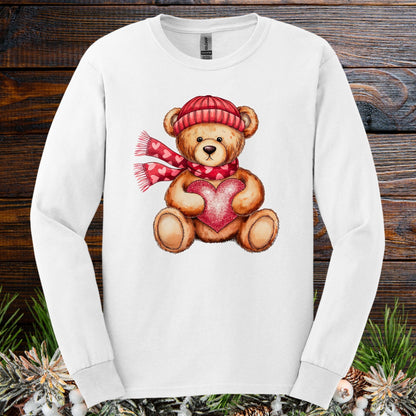White long sleeve tee with watercolor teddy bear wearing red hat, scarf, and holding a glittery red heart.