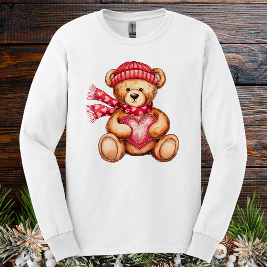 White long sleeve tee with watercolor teddy bear wearing red hat, scarf, and holding a glittery red heart.
