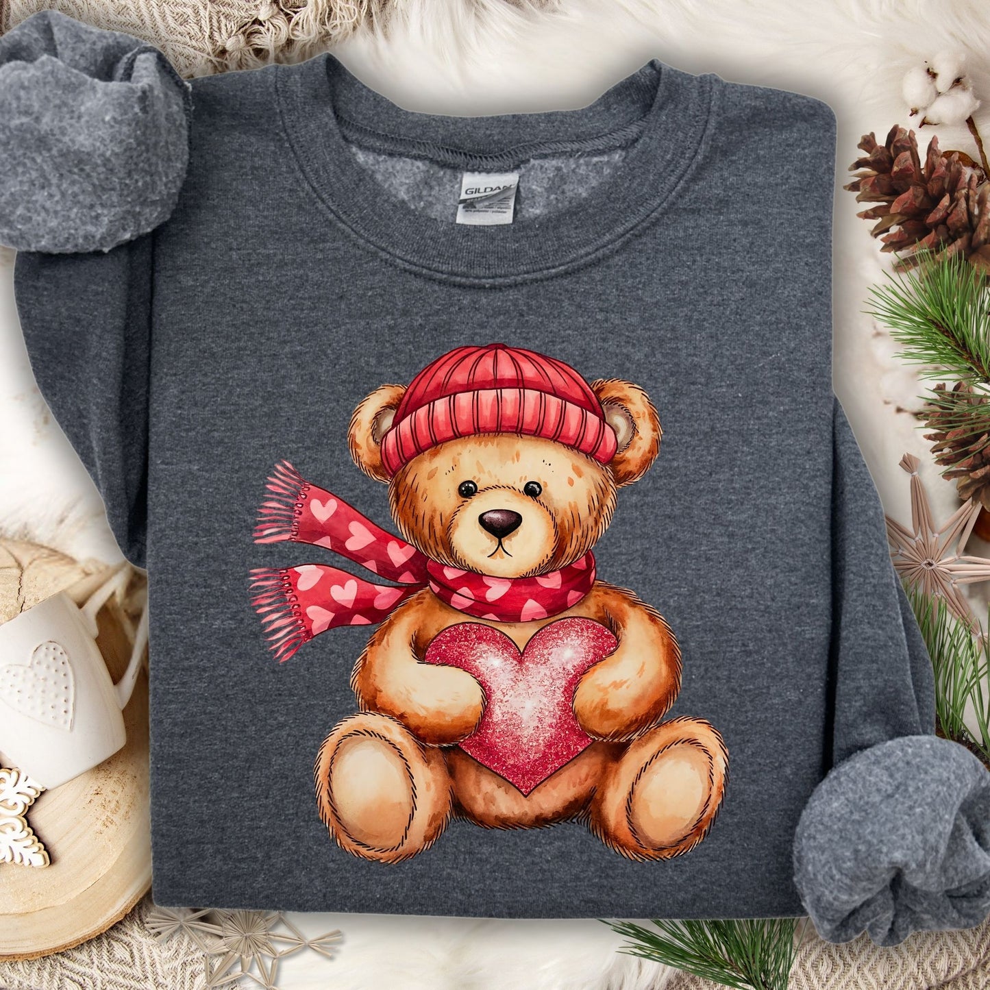 Dark Heather sweatshirt with a teddy bear in a red hat and scarf holding a glittery red heart.