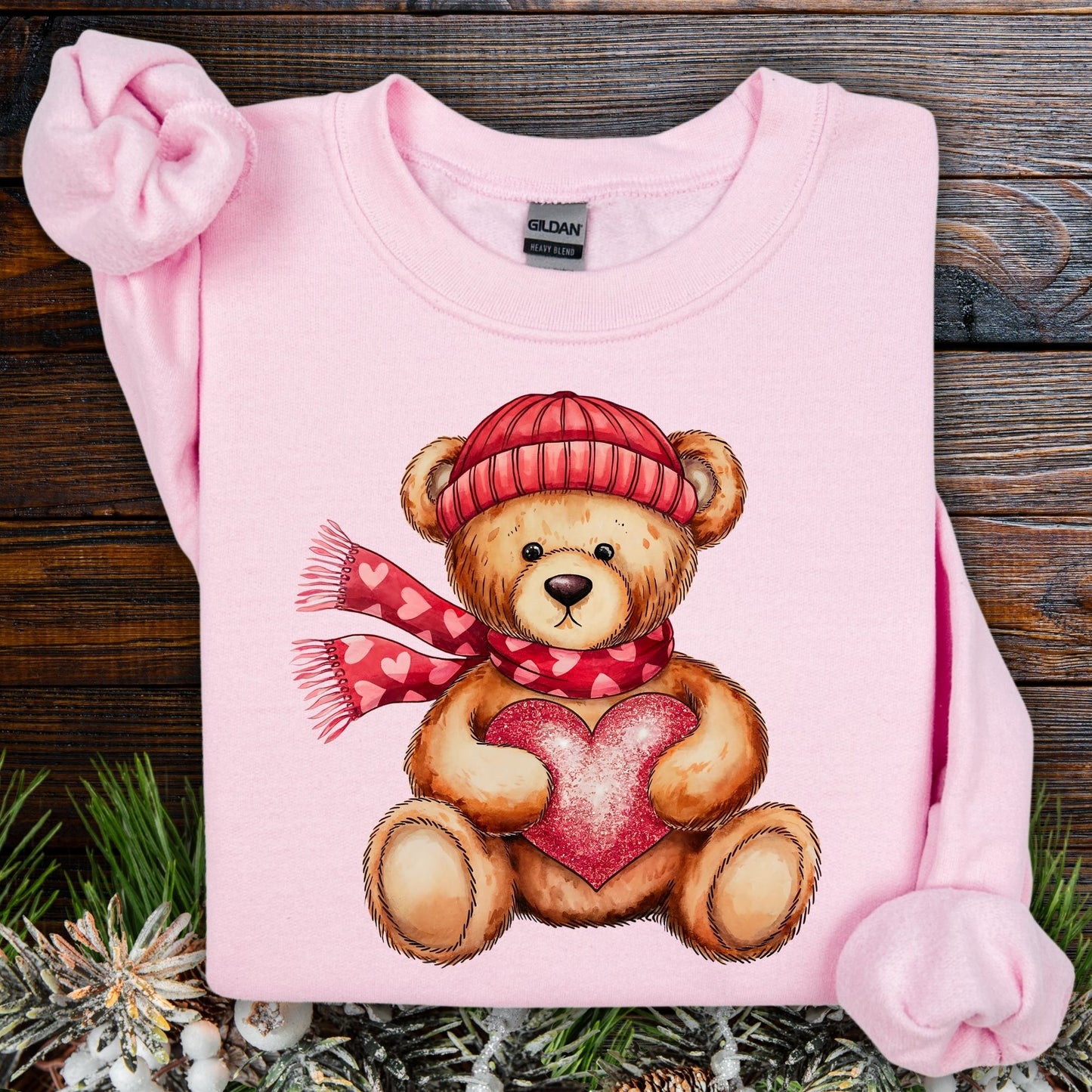 Light pink Gildan sweatshirt with a teddy bear in a red hat and scarf holding a glittery red heart.