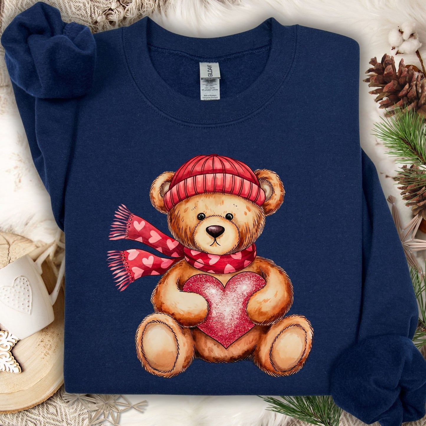 Navy S sweatshirt with a teddy bear in a red hat and scarf holding a glittery red heart.