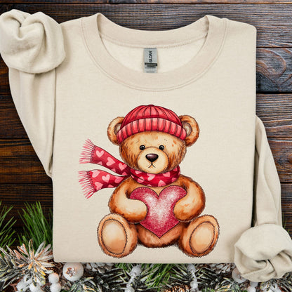 Sand S sweatshirt with a teddy bear in a red hat and scarf holding a glittery red heart.