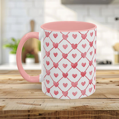 White ceramic mug with pink handle and interior, featuring a watercolor geometric heart pattern.