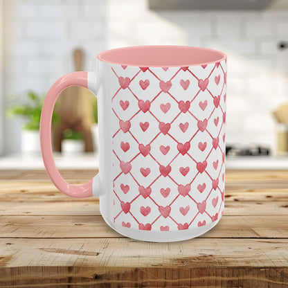 White ceramic mug with a pink interior and handle, featuring a watercolor geometric heart pattern in layered pinks and reds.