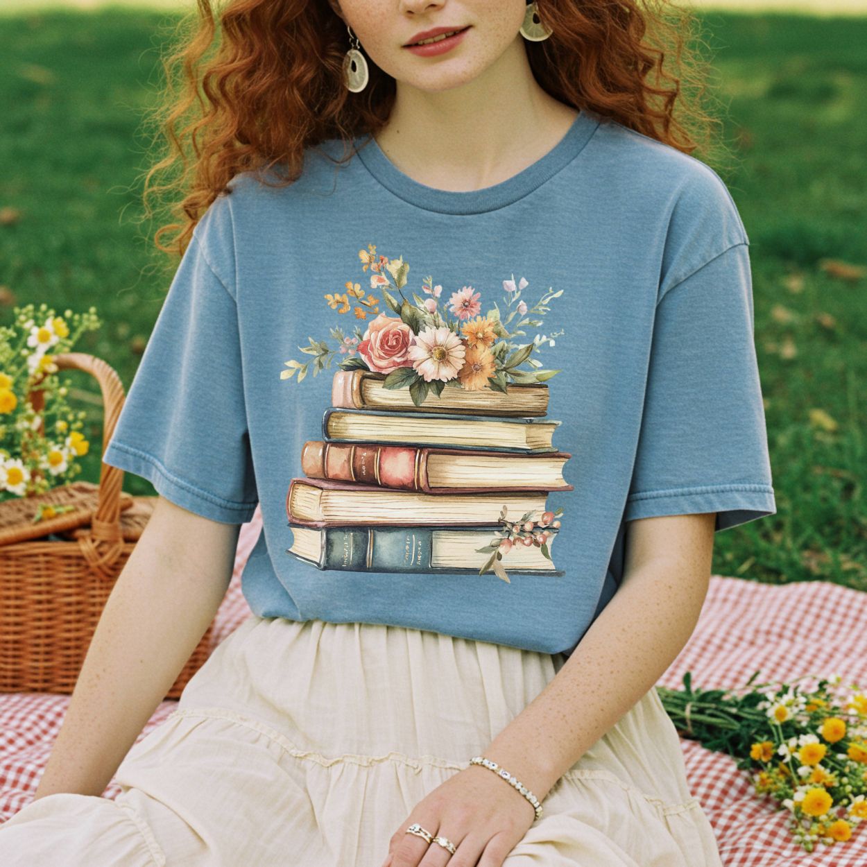 Garment-dyed blue t-shirt with a vintage stack of books and wildflowers graphic.