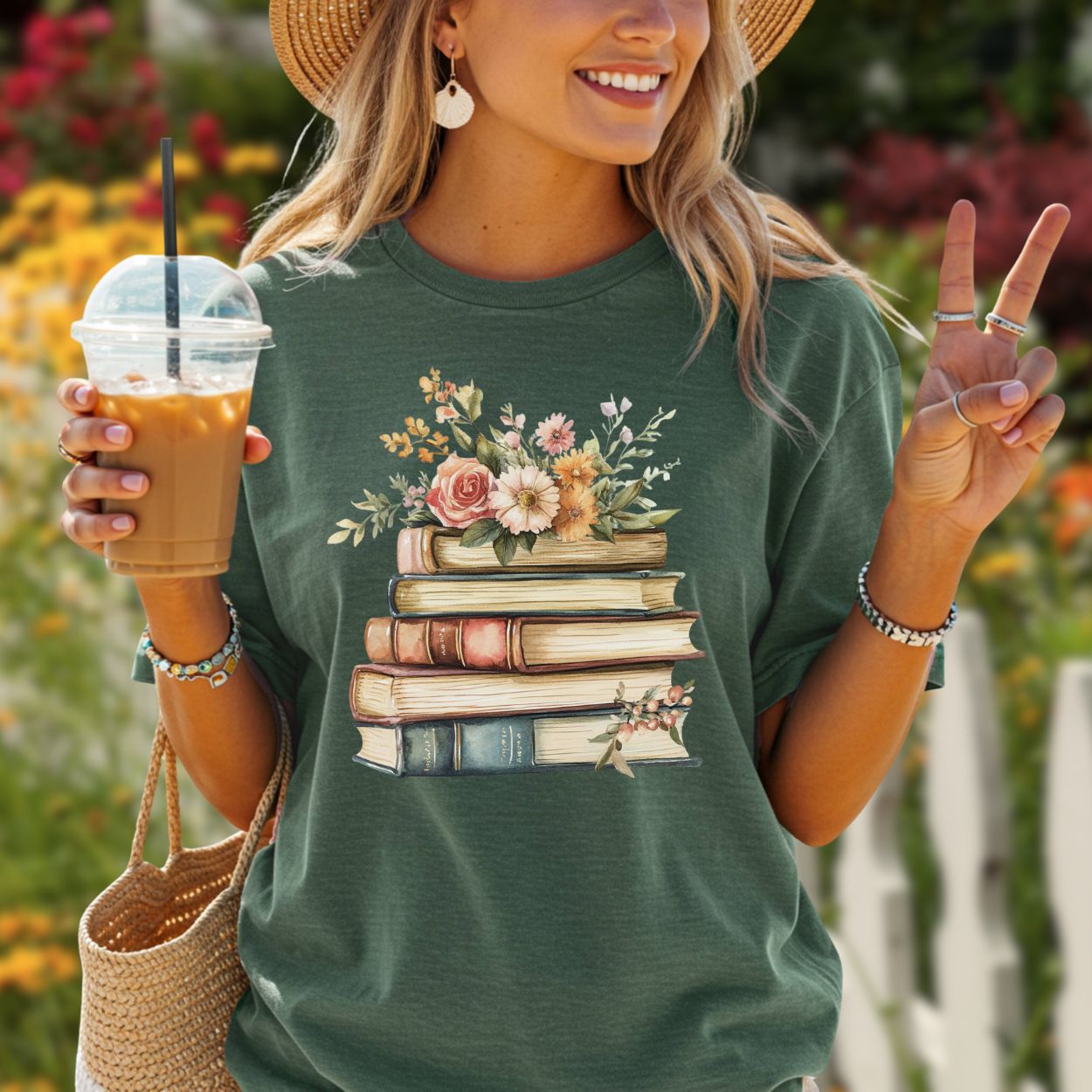 Garment-dyed green t-shirt with a vintage books and wildflowers graphic, worn by a smiling woman.