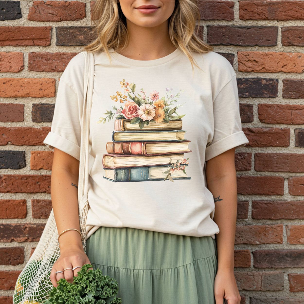 Garment-dyed cream t-shirt with a vintage books and wildflowers graphic, worn by a woman.