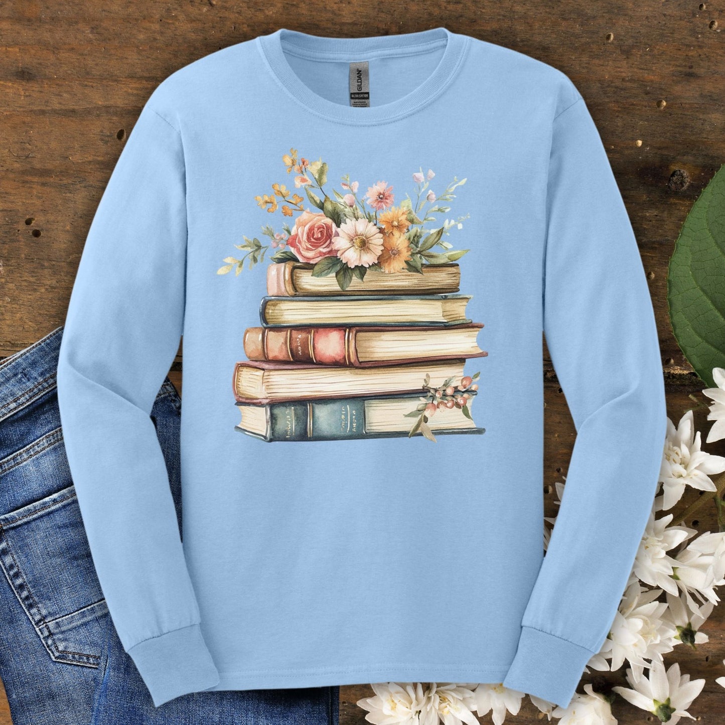 Light blue long sleeve tee, size S, featuring a vintage stack of books blooming with summer flowers.
