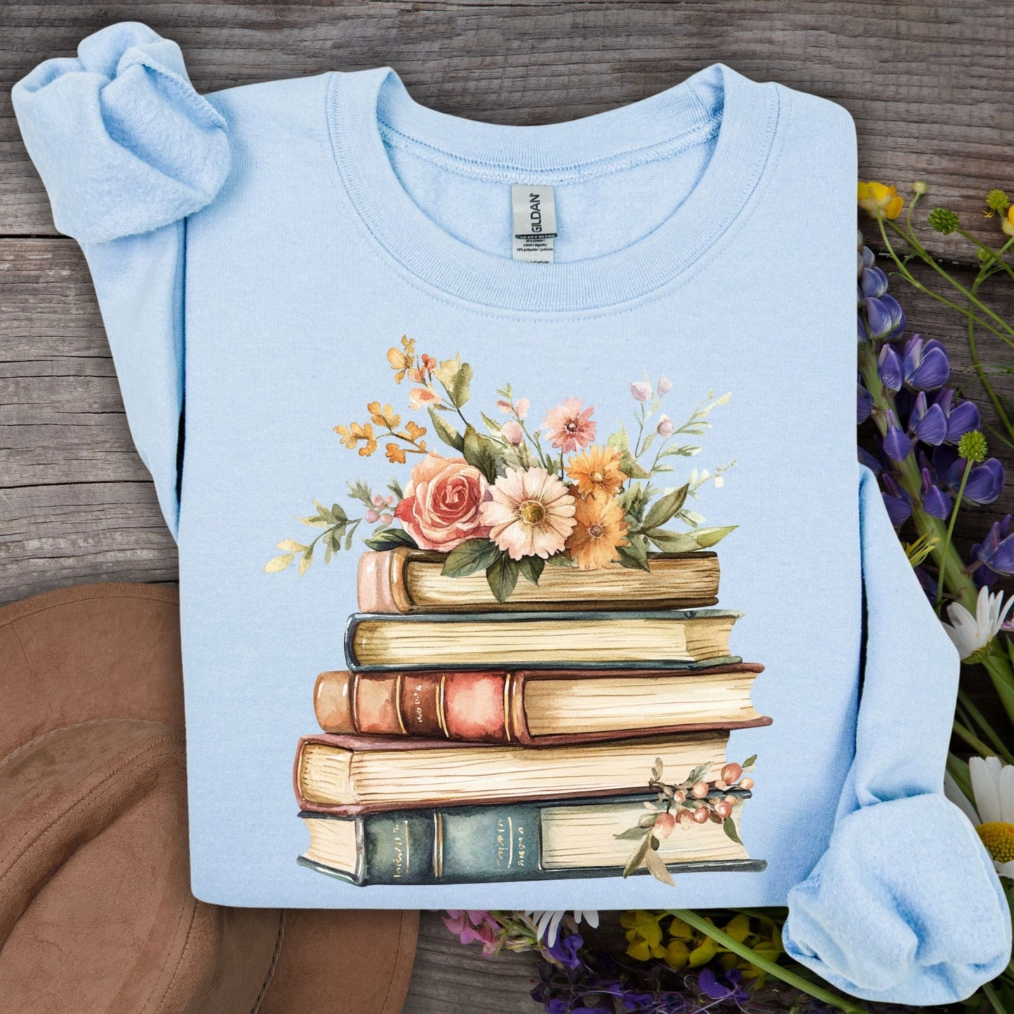 Light blue crewneck sweatshirt with a vintage illustration of stacked books and delicate flowers.