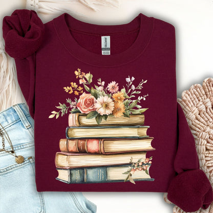 Maroon crewneck sweatshirt with a vintage illustration of stacked books and delicate summer flowers.
