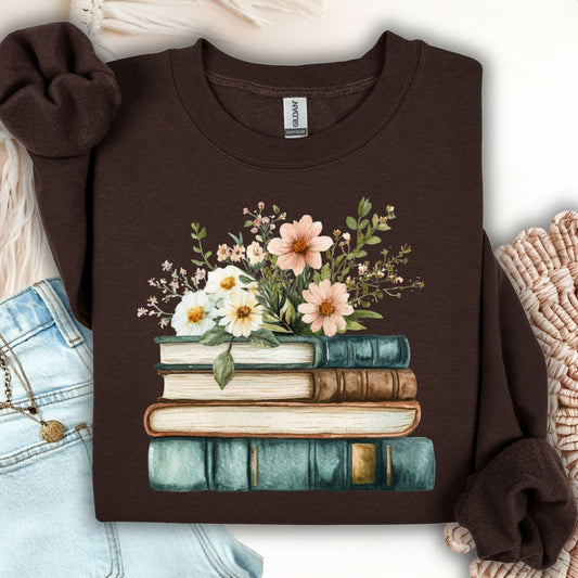 Dark chocolate crewneck sweatshirt with a painterly print of vintage books topped with daisies and soft blooms.