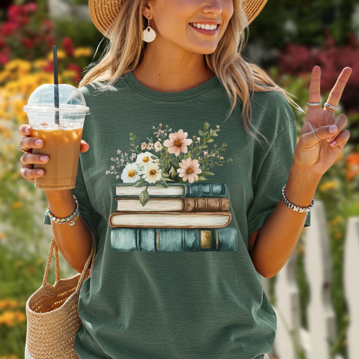 Woman in a relaxed-fit, garment-dyed forest green t-shirt with a stacked books and wildflowers graphic.