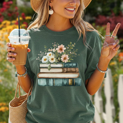 Woman in a relaxed-fit, garment-dyed forest green t-shirt with a stacked books and wildflowers graphic.