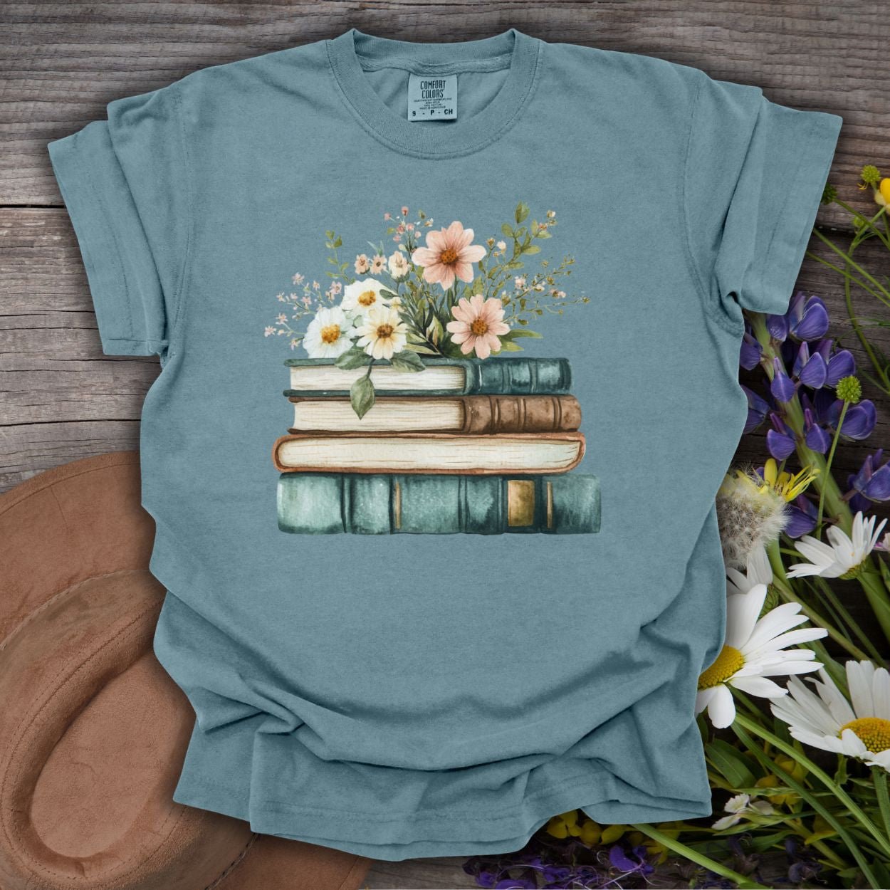 Ice blue garment-dyed t-shirt with a vintage stacked books and wildflowers graphic.