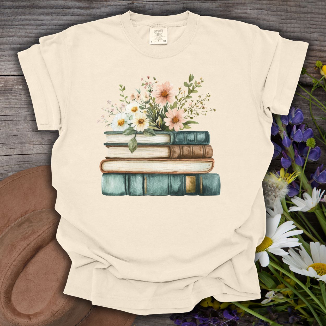Ivory garment-dyed cotton t-shirt with a vintage illustration of stacked books and wildflowers.