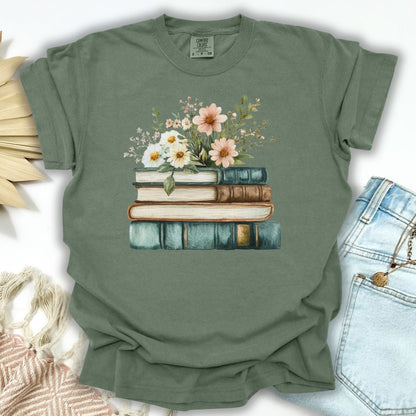 Moss green garment-dyed t-shirt with a stacked books and wildflowers illustration.
