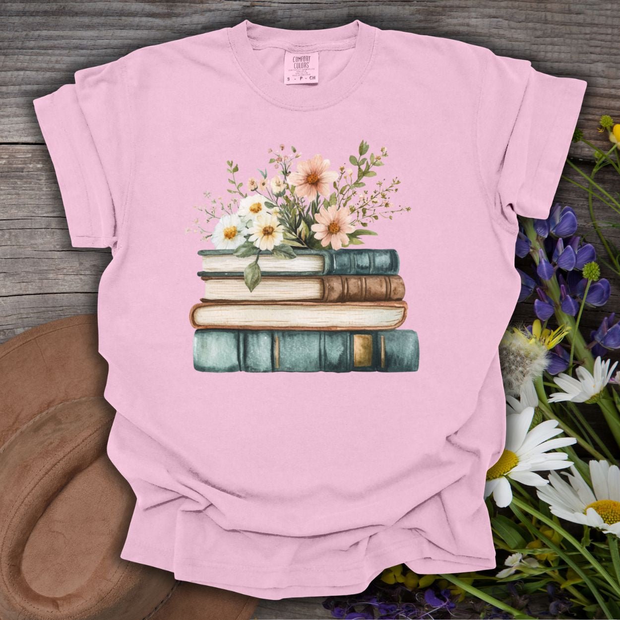 Blossom pink garment-dyed t-shirt with stacked books and wildflowers illustration.