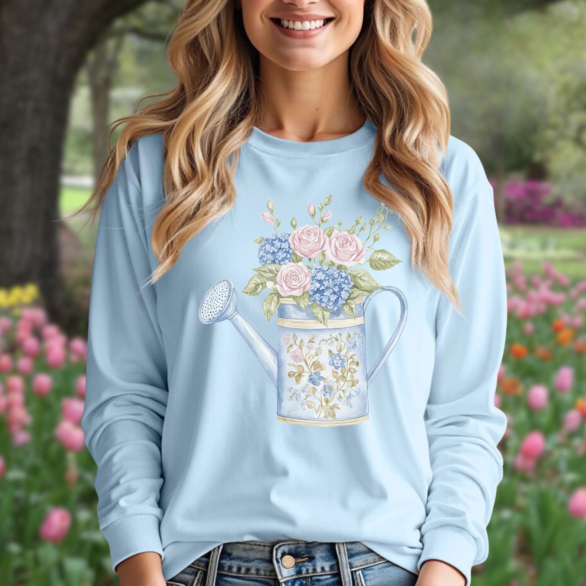 Light blue long sleeve tee with a vintage watering can and watercolor roses, hydrangeas, and greenery.
