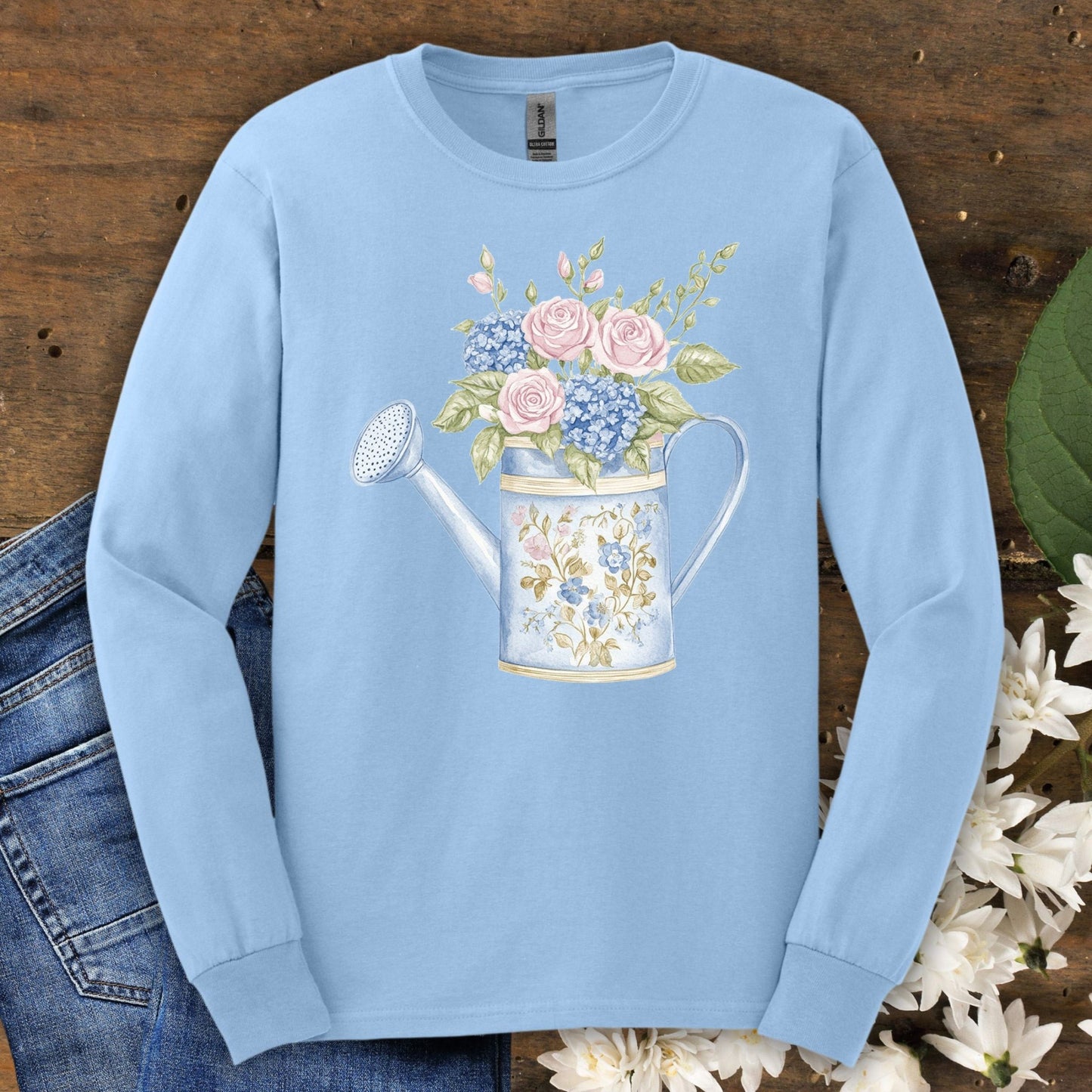 Light blue long sleeve tee with a vintage watering can and pink roses, blue hydrangeas, and greenery.