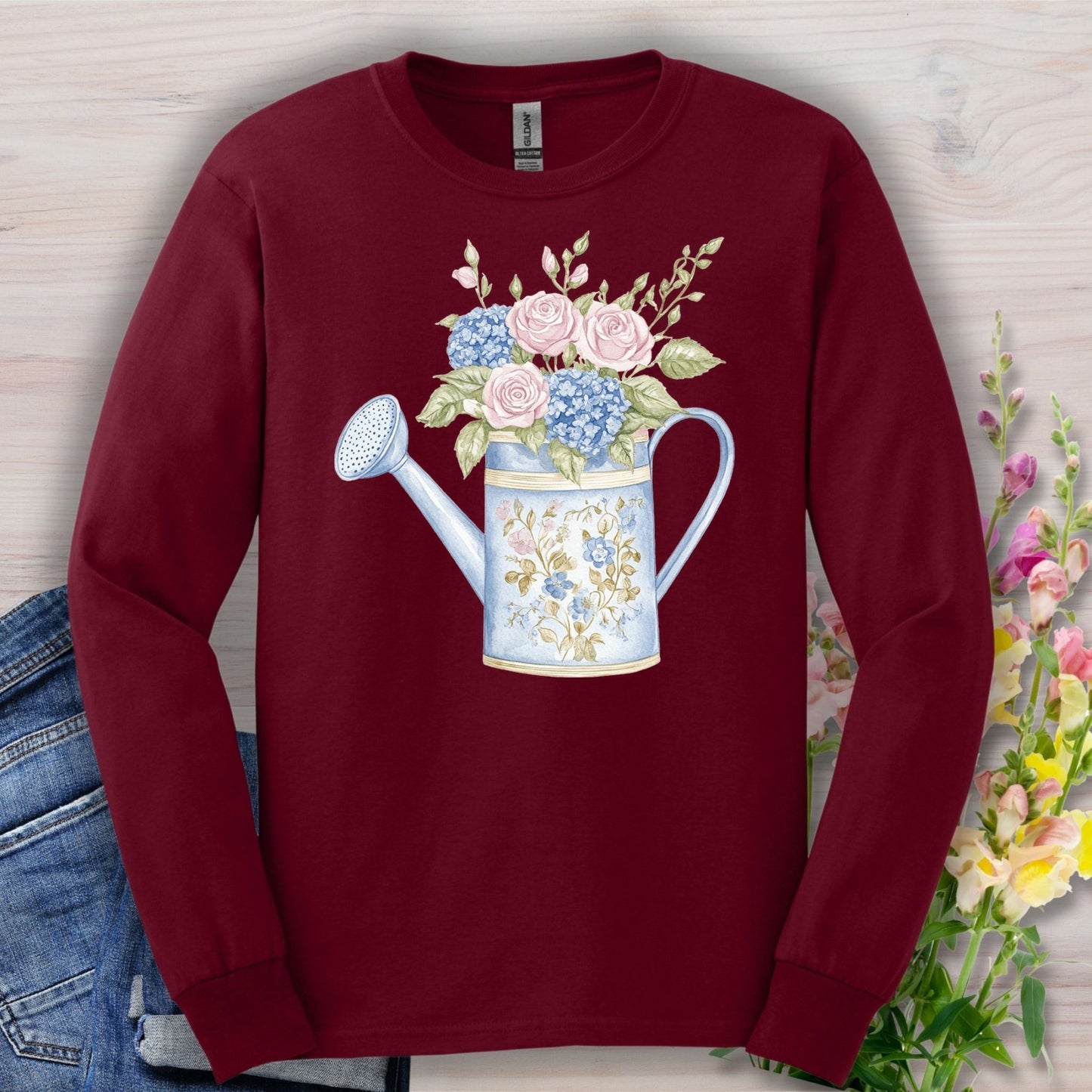 Maroon long sleeve tee with a vintage watering can and roses, hydrangeas, and greenery in watercolor style.
