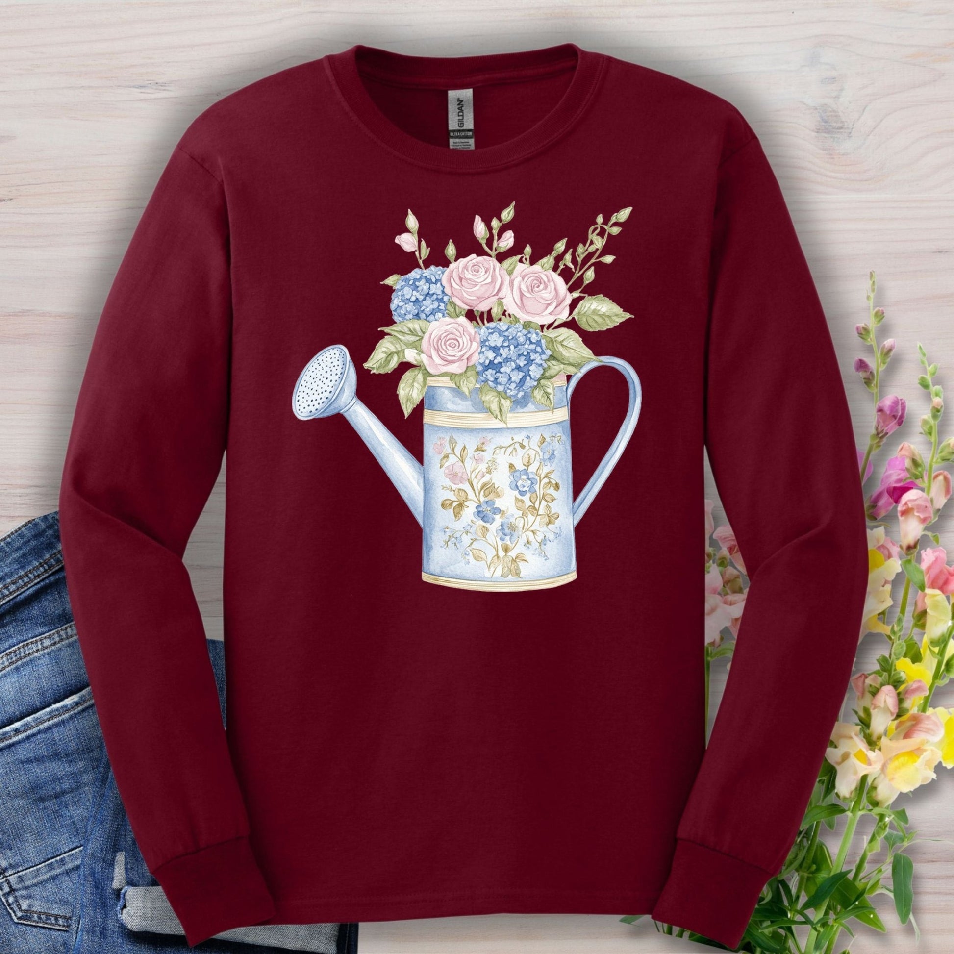 Maroon long sleeve tee with a vintage watering can and roses, hydrangeas, and greenery in watercolor style.