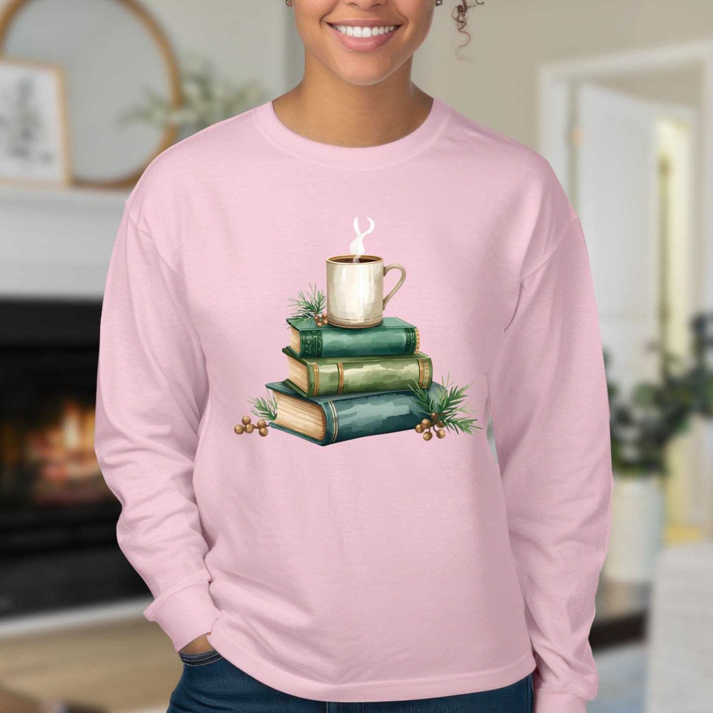 Pink long sleeve tee with a watercolor design of stacked vintage green books and a coffee mug.