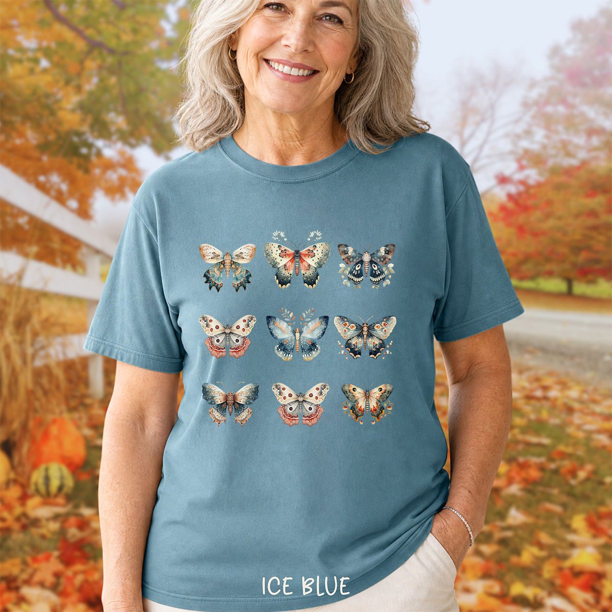 Woman wearing a relaxed-fit ice blue garment-dyed cotton t-shirt featuring a grid of vintage watercolor moth and butterfly illustrations.