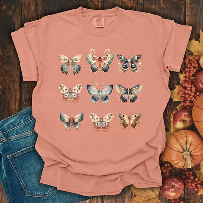 Terracotta garment-dyed cotton t-shirt featuring a grid of vintage watercolor moth and butterfly illustrations.