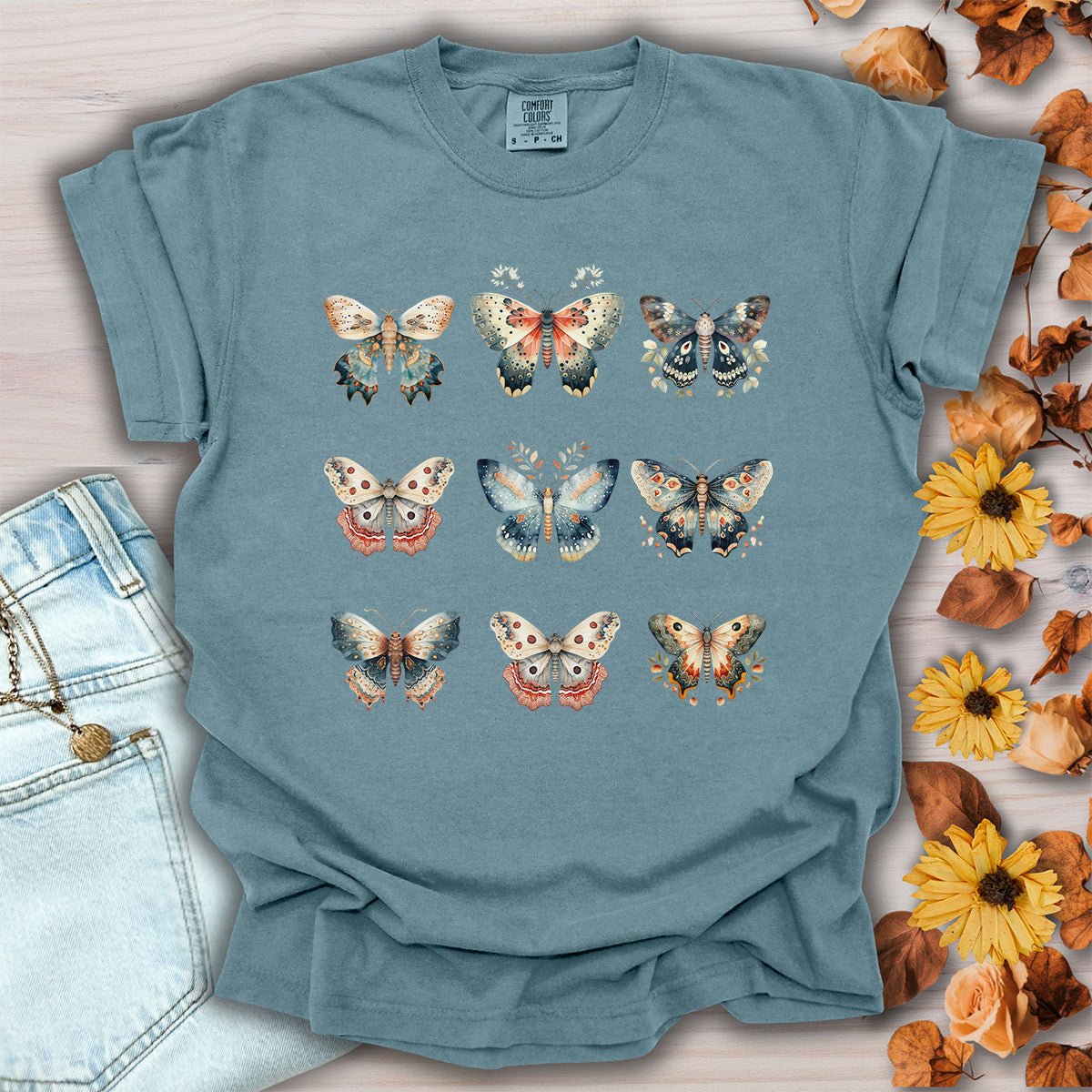 Ice blue garment-dyed cotton t-shirt featuring a vintage watercolor moth and butterfly grid print, size small.